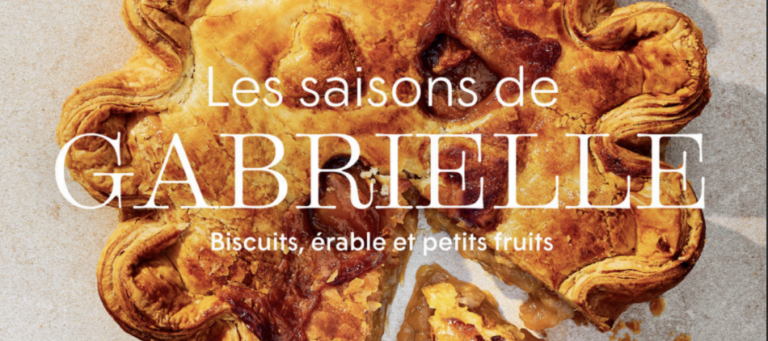 La photo présente la couverture du livre Les saisons de Gabrielle – Biscuits, érable et petits fruits de Gabrielle Rivard-Hiller. En gros plan, on y voit une tarte dorée à la croûte joliment sculptée, dont une part a été retirée, révélant une garniture généreuse et gourmande. La pâte feuilletée est bien dorée, avec des bords artistiquement ondulés, et des coulées de caramel ou de sirop d’érable ajoutent une touche appétissante.