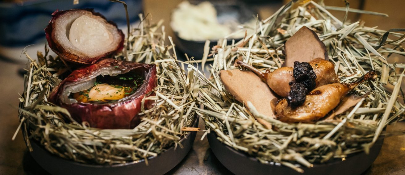 Deux créations artistiques sont présentées sur un lit de foin, évoquant à la fois la nature brute et le raffinement. Chaque élément est soigneusement disposé dans une mise en scène organique, où textures et formes dialoguent dans un équilibre visuel entre rusticité et précision contemporaine.